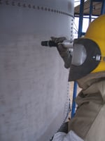 an abrasive blaster cleaning the outside of a tank